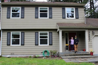 caption: Andrea VanHorn and her fiancee outside their three-bedroom home in North Bend, which she said is a lot more affordable than living in Seattle.