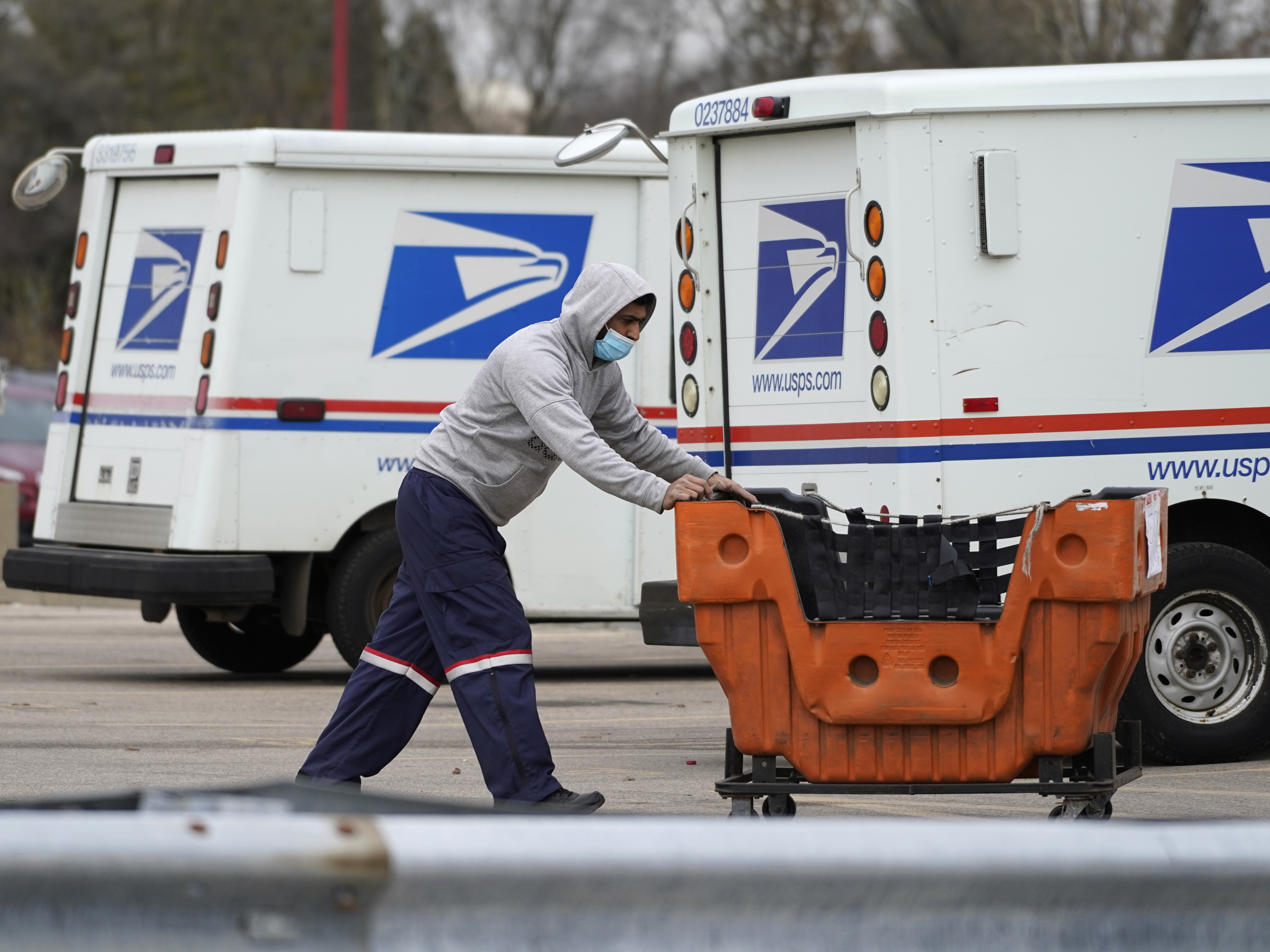 caption: A U.S. Postal Service employee works outside a post office in Wheeling, Ill., on Dec. 3, 2021.