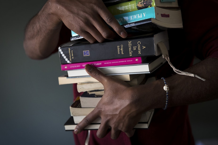 caption: Jordan packs his belongings, including a book titled 'A Course in Miracles,' at his studio apartment on Tuesday, February 26, 2019, after receiving an eviction notice following a late paycheck, on 4th Avenue South in Seattle.