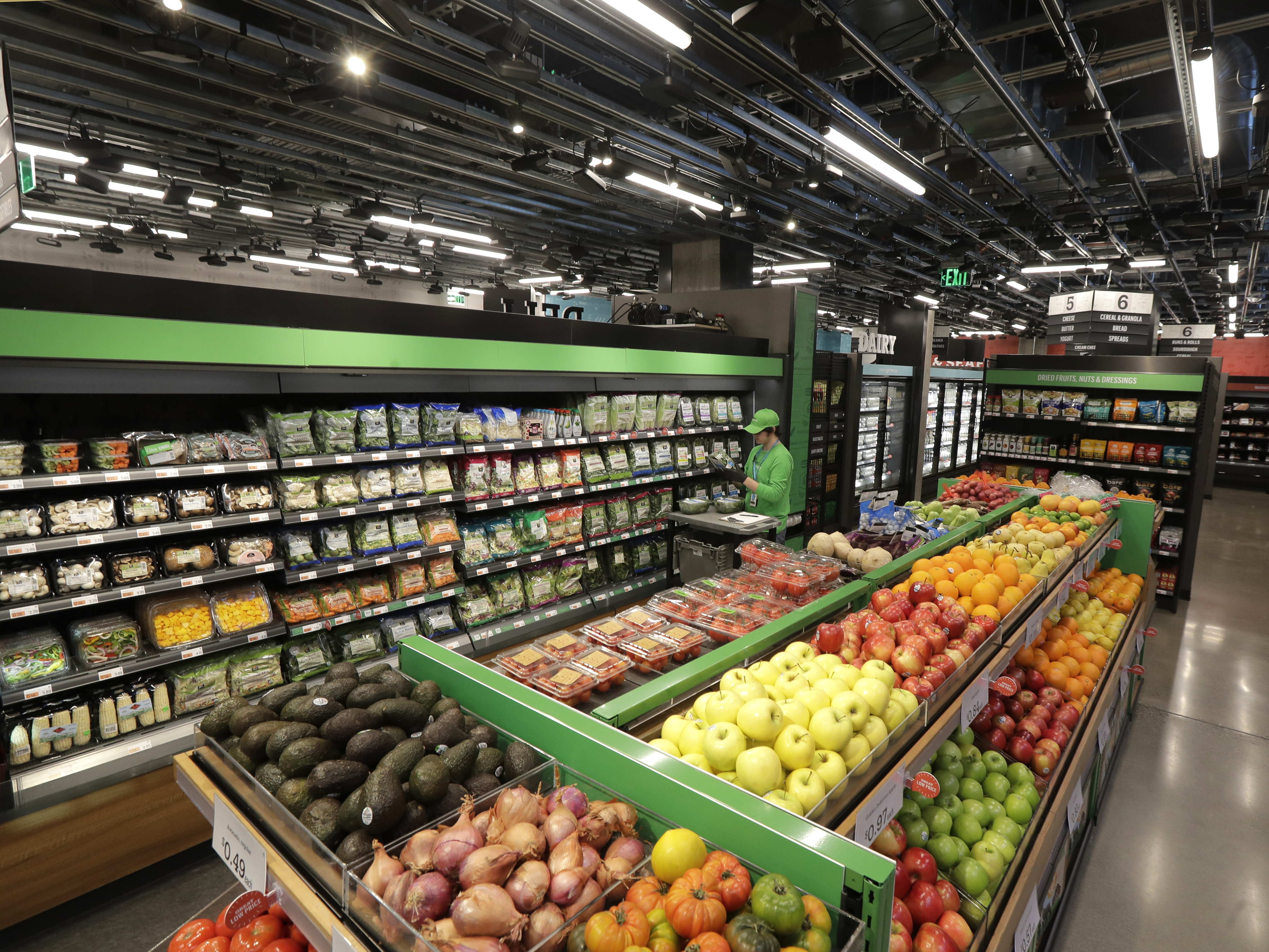 caption: In this Feb. 21, 2020 photo, a worker checks items on a shelf in the produce section of an Amazon Go Grocery store set to open soon in Seattle's Capitol Hill neighborhood.