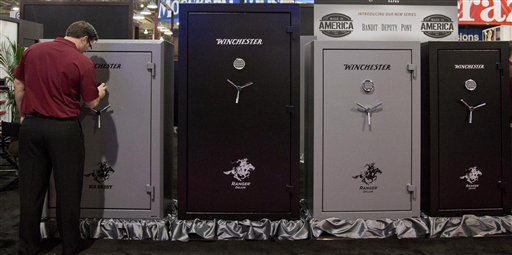 caption: A Winchester Safes representative sets the lock on one of several gun safes on display at the 35th annual SHOT Show, Tuesday, Jan. 15, 2013, in Las Vegas.