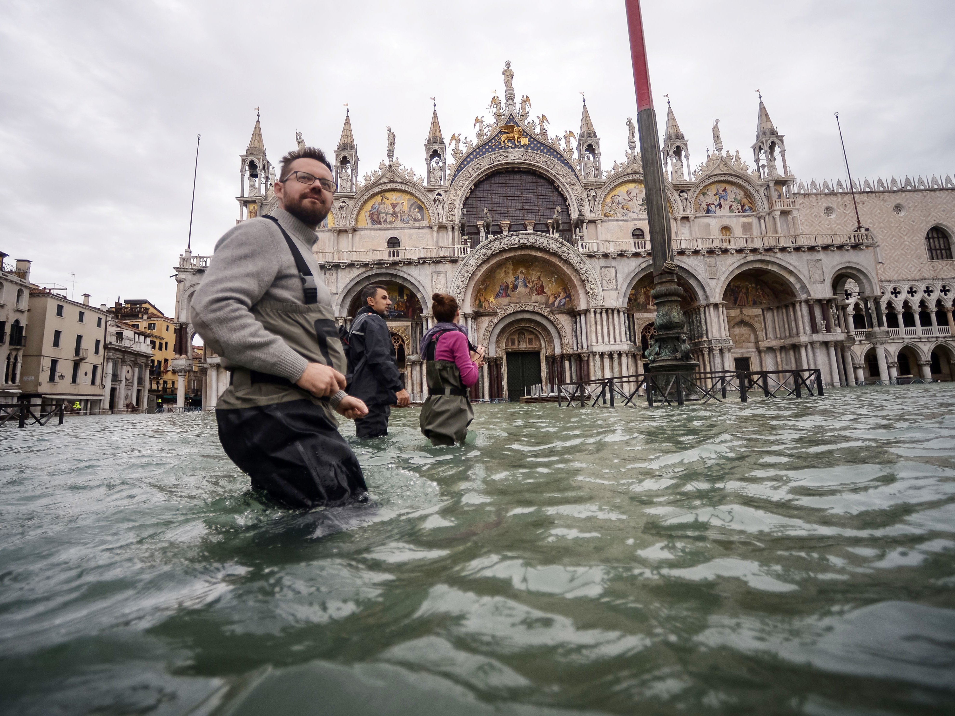 caption: Tourists walk across flooded St. Mark's Square two days after Venice suffered its highest tide in 50 years.