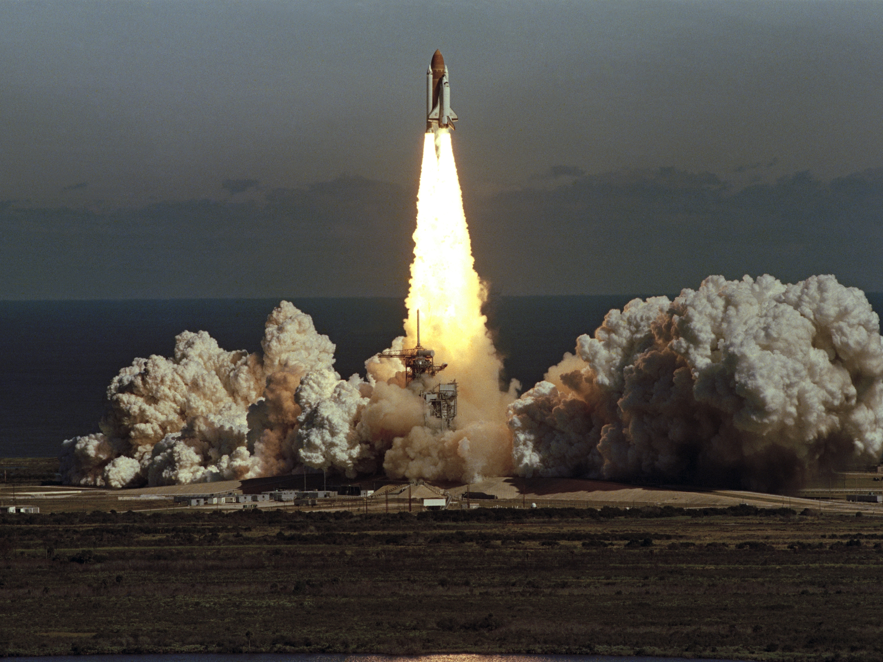 caption: The space shuttle Challenger lifts off from Kennedy Space Center in Florida on Jan. 28, 1986, in a cloud of smoke with a crew of seven aboard. The shuttle exploded shortly after this photo.