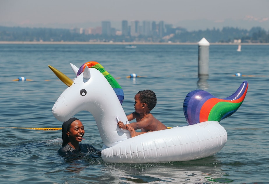 caption: Oromiya Robale holds her brother Yusuf, 2, on a unicorn float as they cool off in Lake Washington at Mount Baker Beach on the hottest day of the year, Monday, June 28.