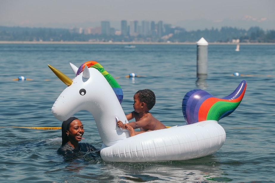 caption: Oromiya Robale holds her brother Yusuf, 2, on a unicorn float as they cool off in Lake Washington at Mount Baker Beach on the hottest day of the year, Monday, June 28.