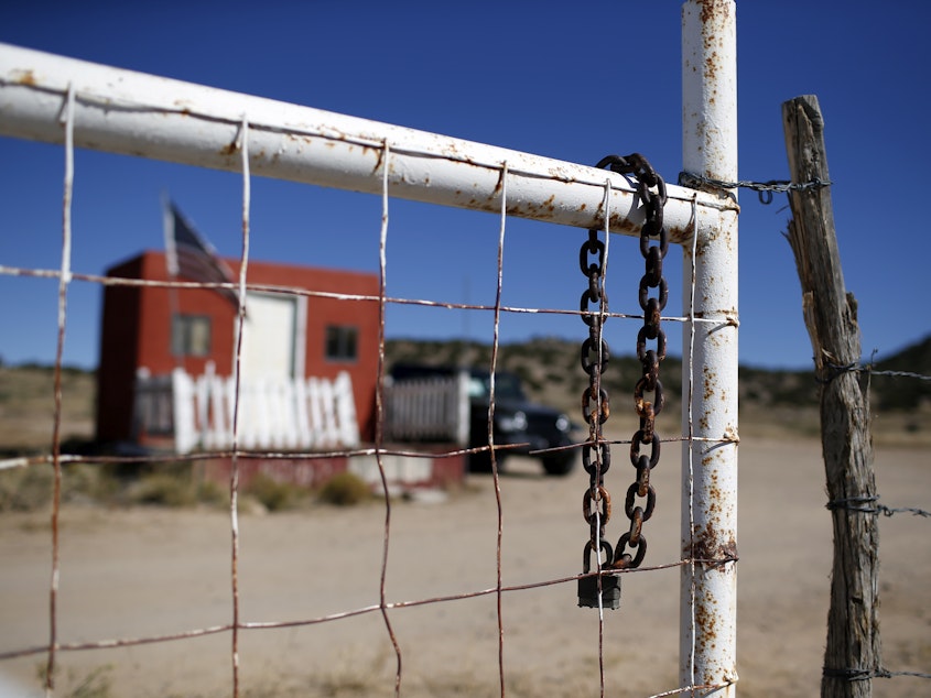 caption: A rusted chain hangs on the fence at the entrance to the Bonanza Creek Ranch film set in Santa Fe, N.M., on Oct. 27, 2021.