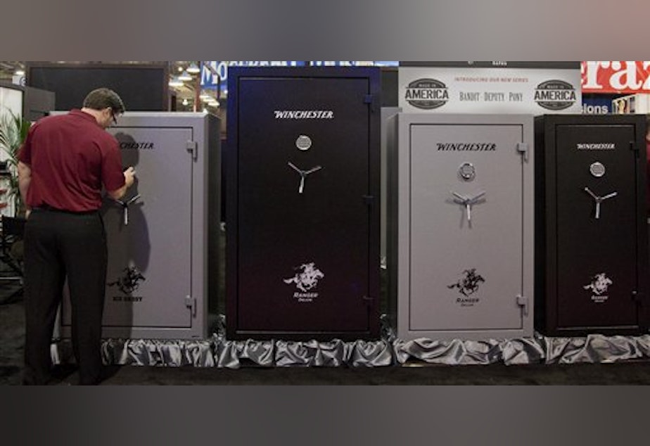caption: A Winchester Safes representative sets the lock on one of several gun safes on display at the 35th annual SHOT Show, Tuesday, Jan. 15, 2013, in Las Vegas.