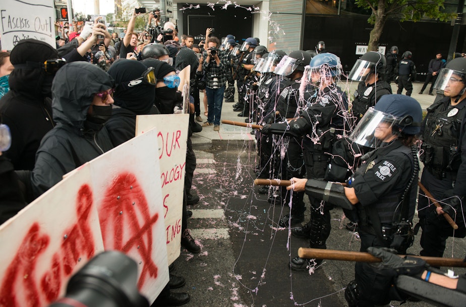 caption: Protesters sprayed Seattle Police with silly string moments before attempting to break the line. Click or tap on the image for slideshow.