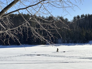 caption: An ice fisherman stands on the frozen Molly's Falls Pond in Marshfield, Vt., on Sunday.