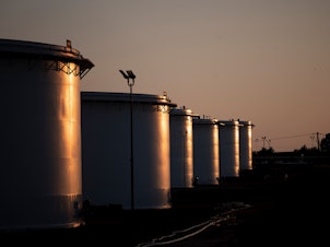 The sun sets behind a crude oil storage facility in Cushing, Oklahoma, on May 4, 2020. The IEA's 31 members plan to release 120 million of barrels of oil from their emergency reserves, half of which will come from the U.S. as part of a previously announced drawdown of its stockpiles.