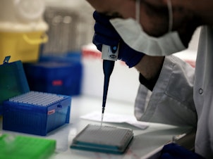 caption: A scientist works on COVID-19 samples to find variations of the virus at the Croix-Rousse Hospital laboratory in Lyon, France, in January.