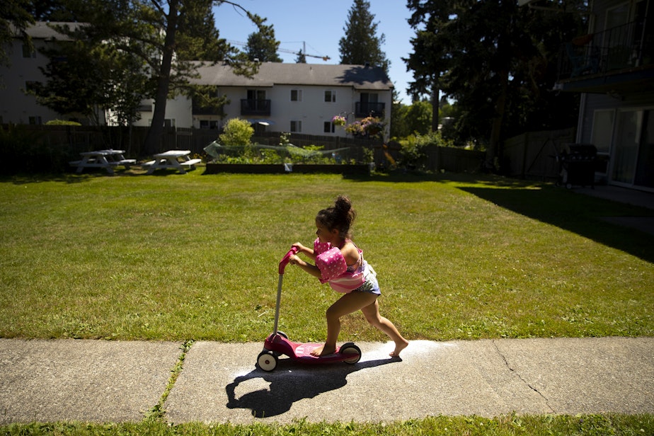 caption: Vay, 5, rides a scooter on Friday, July 15, 2022, outside of the family's apartment complex. 