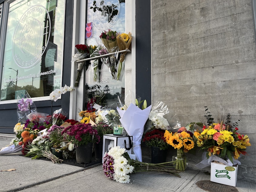 caption: The front of The Postman in Seattle's Central District is lined with flowers Thursday, Oct. 20, following the death of its founder D’Vonne Pickett, Jr. Pickett was shot at a nearby bus stop on Wednesday, Oct. 19. 