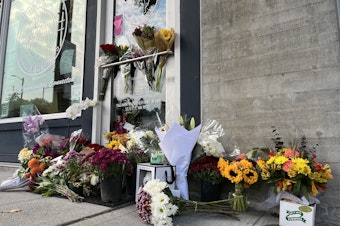 caption: The front of The Postman in Seattle's Central District is lined with flowers Thursday, Oct. 20, following the death of its founder D’Vonne Pickett, Jr. Pickett was shot at a nearby bus stop on Wednesday, Oct. 19. 