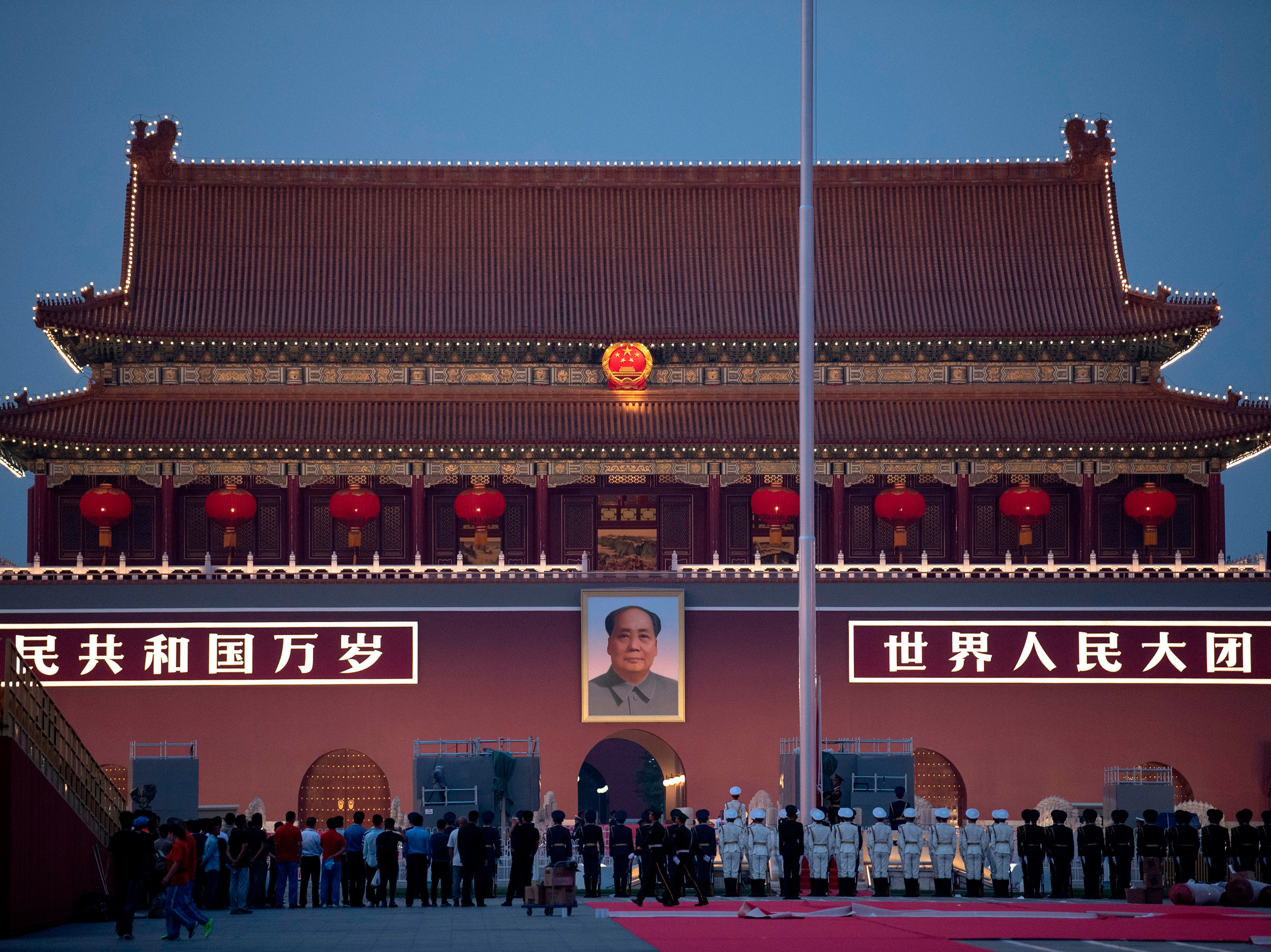 caption: Chinese honor guards stand in formation during the lowering of the national flag in front of Tiananmen Gate in Beijing on Monday, one day before the 70th anniversary of the founding of the People's Republic of China.