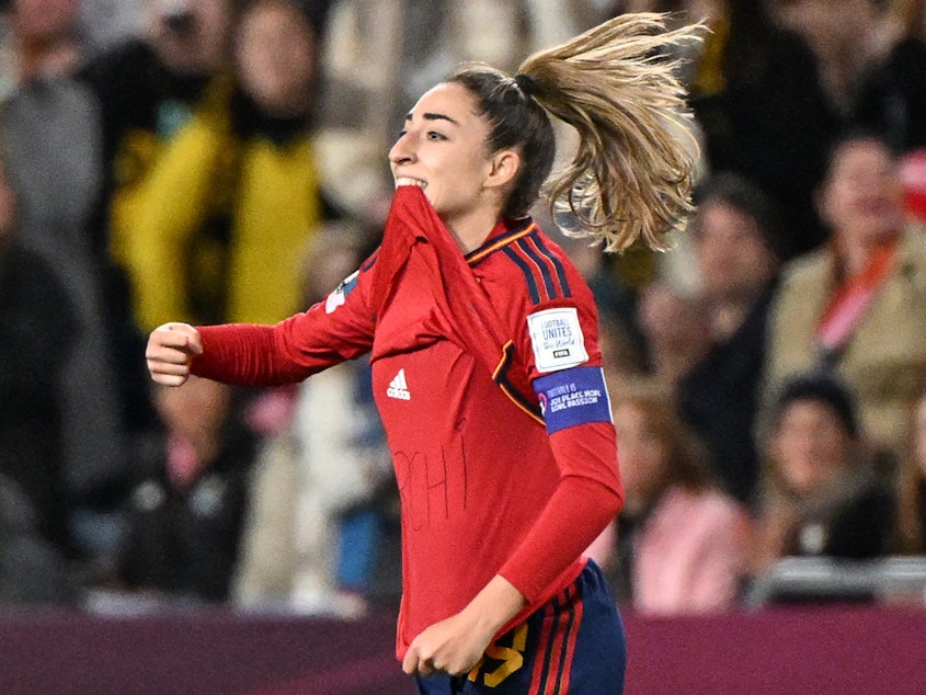 caption: Spain's Olga Carmona points to the message she had written on her undershirt to honor the death of one of her best friend's mother after scoring what would be the only goal in the match against England on Sunday. Carmona later learned that her father had died before the final match.