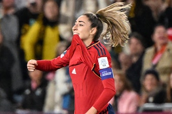 caption: Spain's Olga Carmona points to the message she had written on her undershirt to honor the death of one of her best friend's mother after scoring what would be the only goal in the match against England on Sunday. Carmona later learned that her father had died before the final match.
