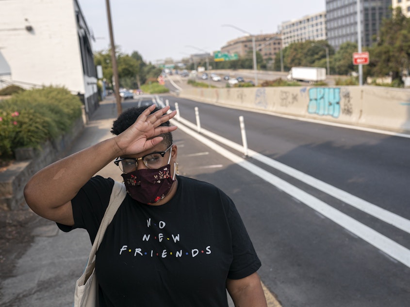 caption: Katherine Morgan wipes sweat from her forehead while walking to work during a record-breaking heat wave in Portland in 2021. Scientists say that heat wave would have been virtually impossible without human caused climate change.