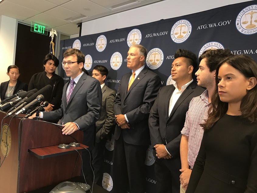 caption: Attorney General Bob Ferguson and Gov. Jay Inslee of Washington state, surrounded by DACA recipients, denounce the Trump Administration's plan to end the federal protection program for young immigrants. 
