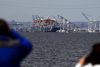 caption: Francis Scott Key Bridge collapsed after being hit by the Dali container vessel, as seen from Riviera Beach, Md., on Tuesday.