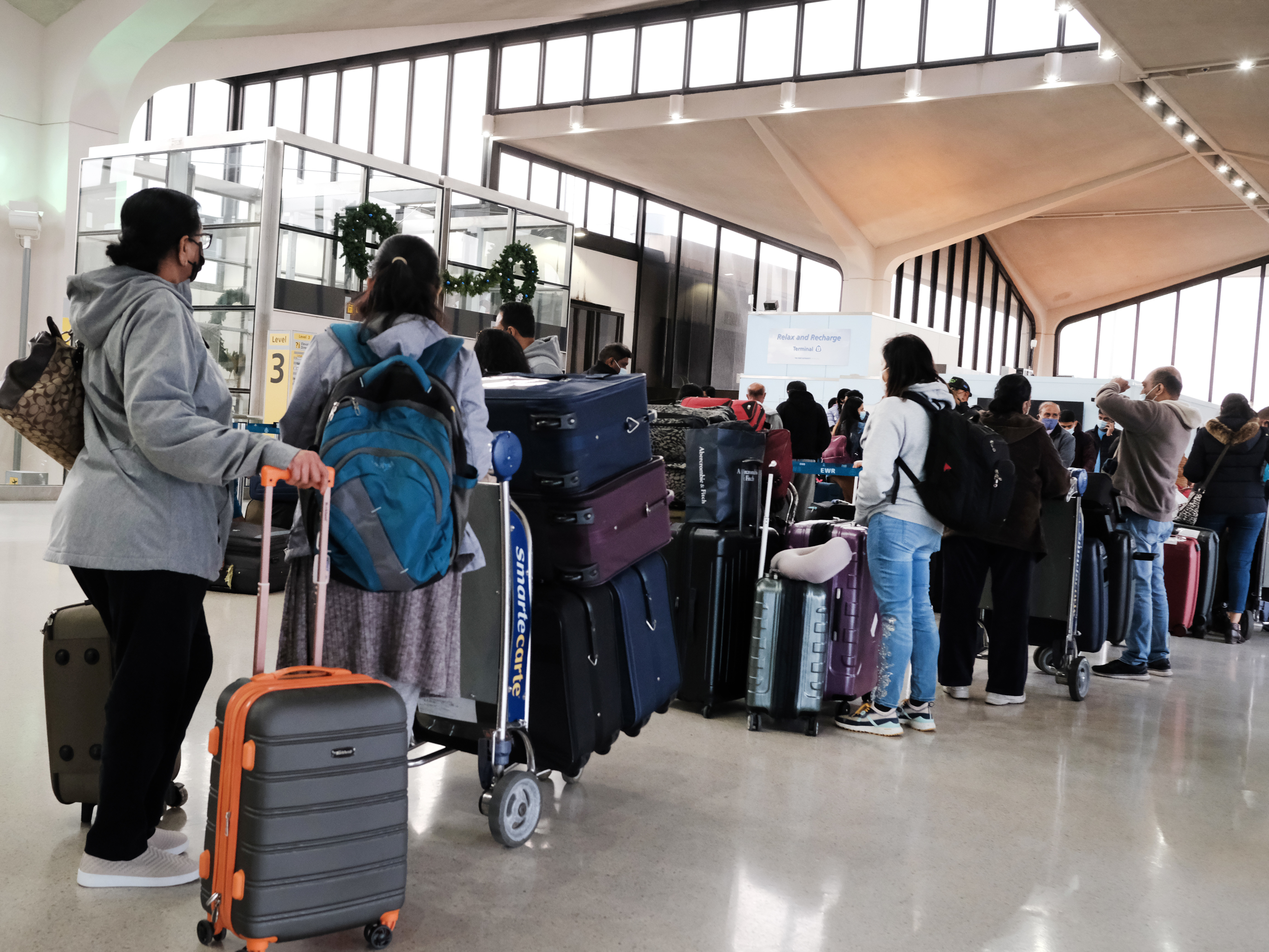 caption: Travelers arrive for flights at Newark Liberty International Airport in New Jersey on Nov. 30.