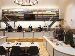 caption: Defendant Anwar Raslan (right) and others involved in his trial stand in the Higher Regional Court in Koblenz, Germany, at the start of a trial session last month. Raslan was put on trial in April 2020 in a landmark case in Germany.