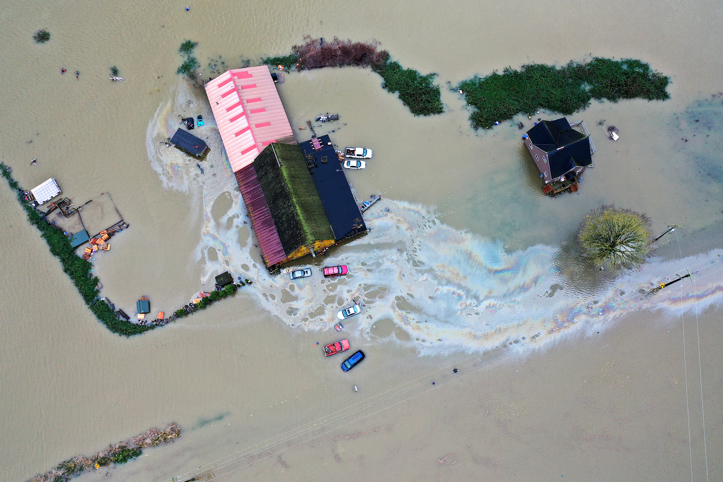 caption: Homes are shown surrounded by floodwater following consecutive atmospheric rivers on Thursday, December 11, 2025, near Mount Vernon. 
