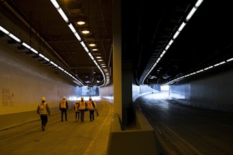 caption: Members of the media walk toward the the tunnel's northbound on-ramp, left, on Thursday, November 15, 2018, inside the State Route 99 tunnel in Seattle.