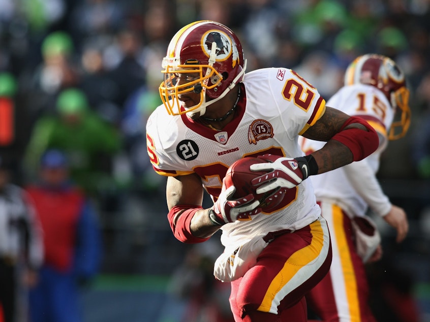 caption: Former Washington Football Team running back Clinton Portis carries the ball during an NFL wildcard playoff football game against the Seattle Seahawks in Jan. 2008. Portis plead guilty to health care fraud charges Tuesday, authorities said.