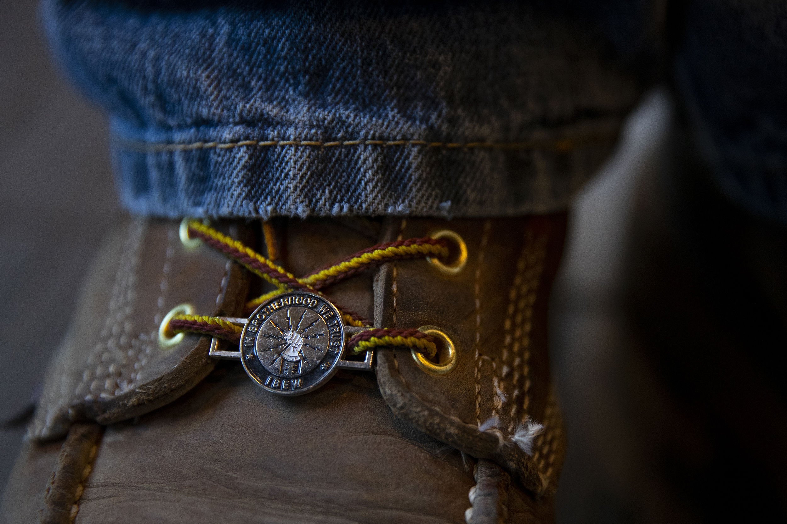 caption: Electrician Jimmy Ortega wears an IBEW boot charm that reads, ‘in brotherhood we trust,’ at IBEW Brotherhood Night on Thursday, July 17, 2025, at Monkey N’Around Pizza in Quincy, Washington. 