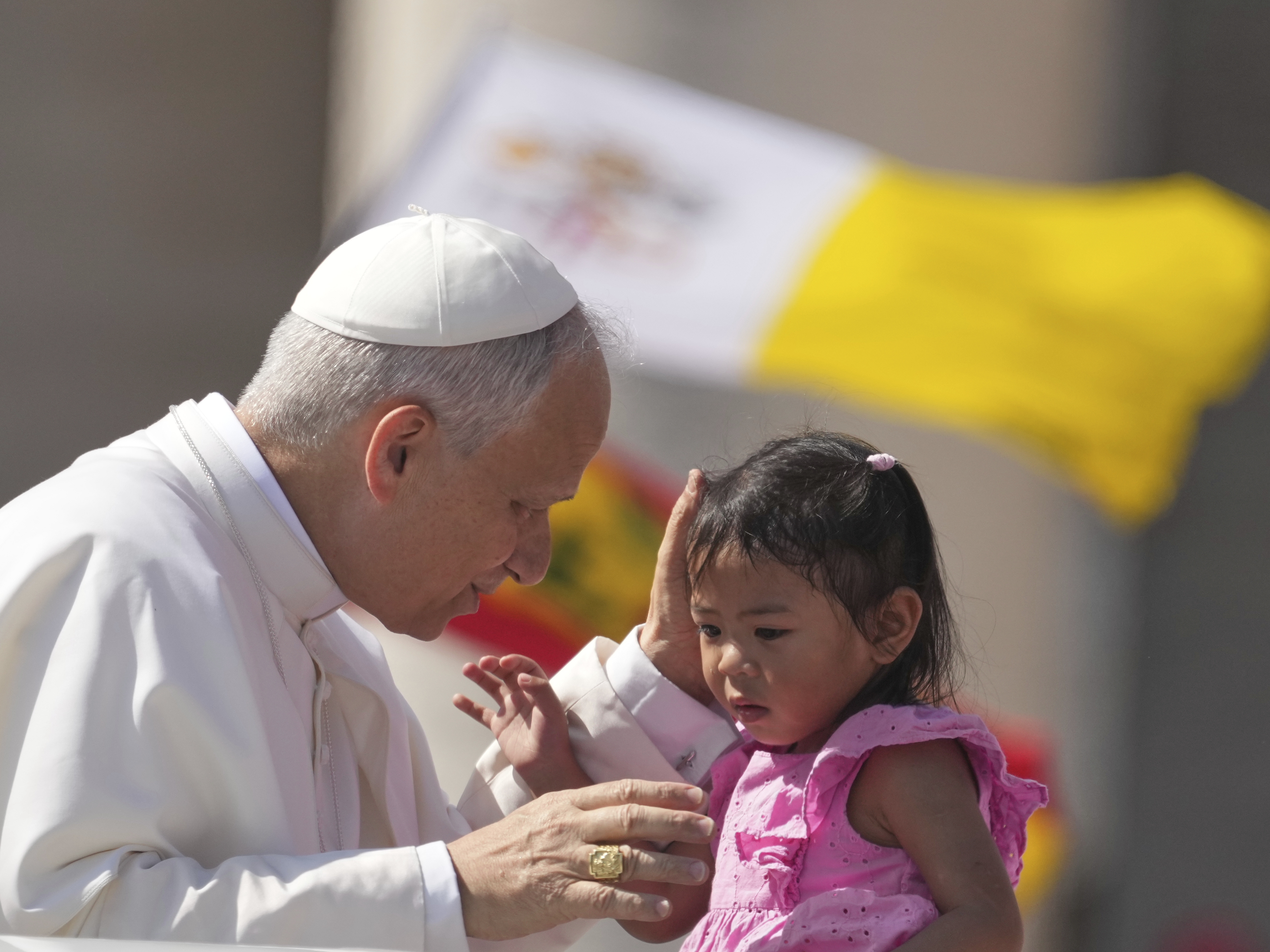caption: Pope Leo XIV caresses a little girl as he arrives to celebrate a Mass for the Jubilee of New Religious Associations on Pentecost Day in St. Peter's Square at the Vatican, Sunday, June 8, 2025.