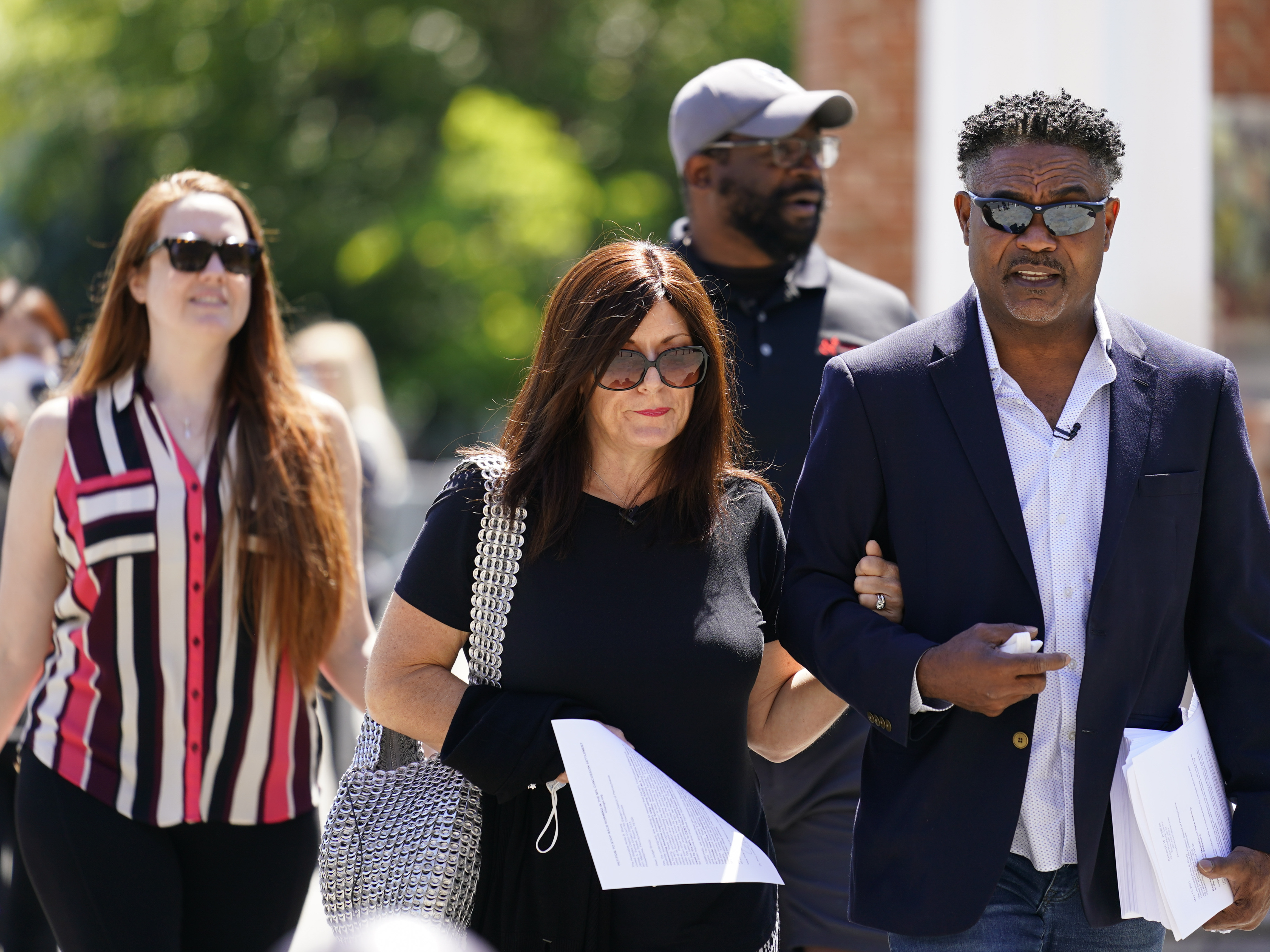 caption: Former NFL players Ken Jenkins, right, and Clarence Vaughn III, center right, along with their wives, Amy Lewis, center, and Brooke Vaughn, left, carry petitions demanding equal treatment for everyone involved in the settlement of concussion claims against the NFL, to the federal courthouse in Philadelphia, in this Friday, May 14, 2021, file photo.