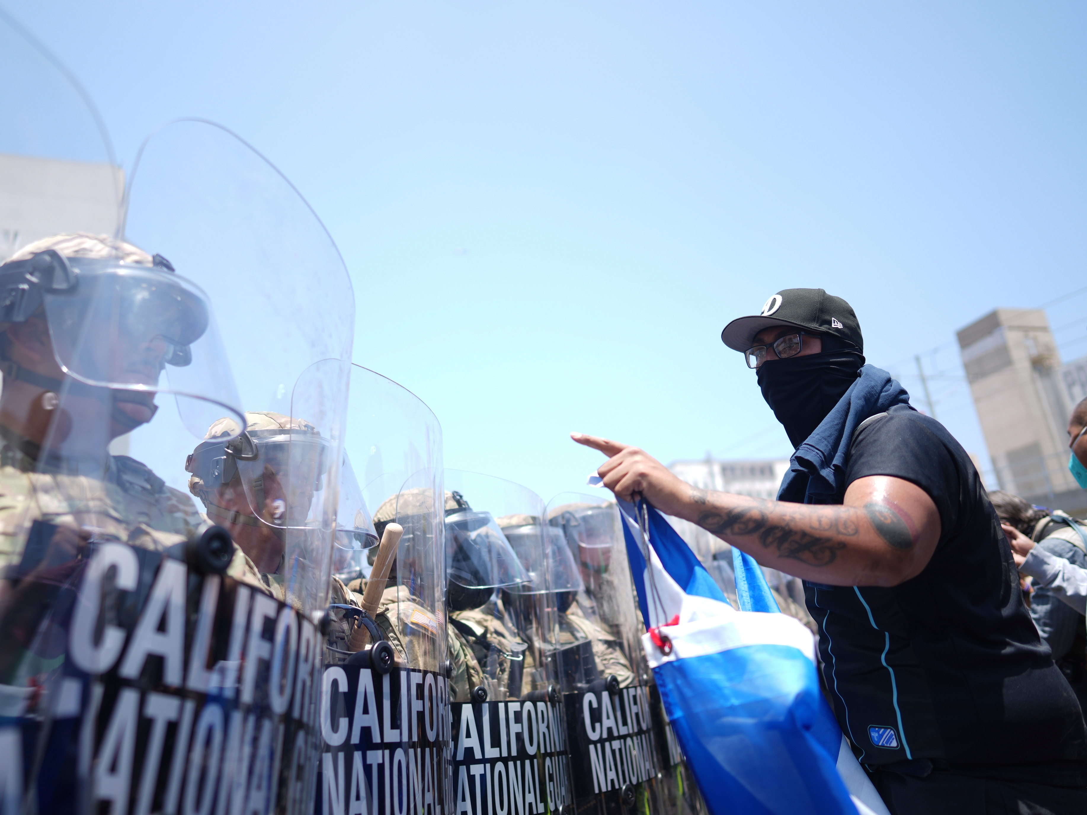 caption: A protester confronts a line of California National Guard in the metropolitan detention center of downtown Los Angeles on Sunday.