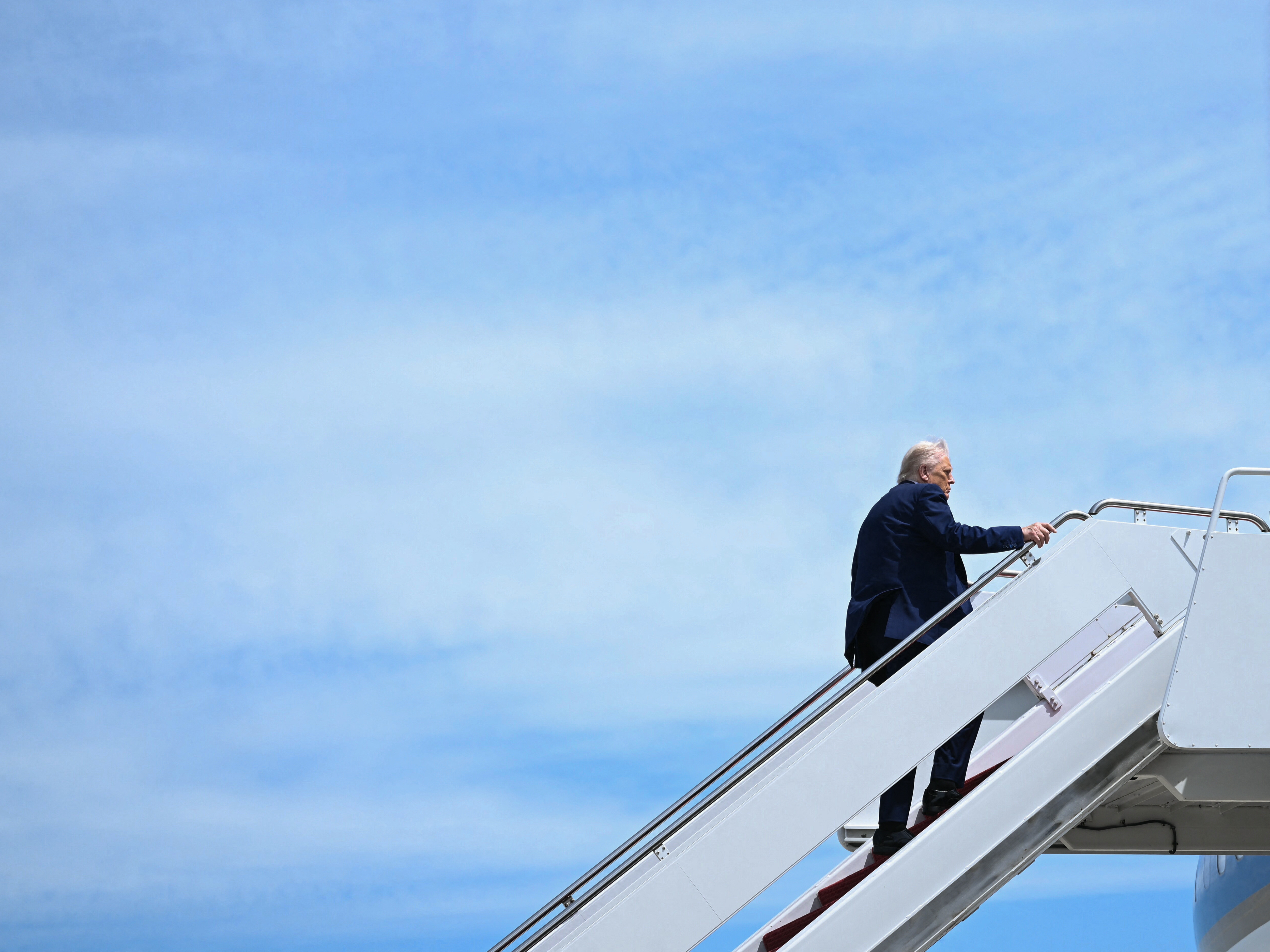 caption: President Trump boards Air Force One at Joint Base Andrews in Maryland on May 12, 2025.