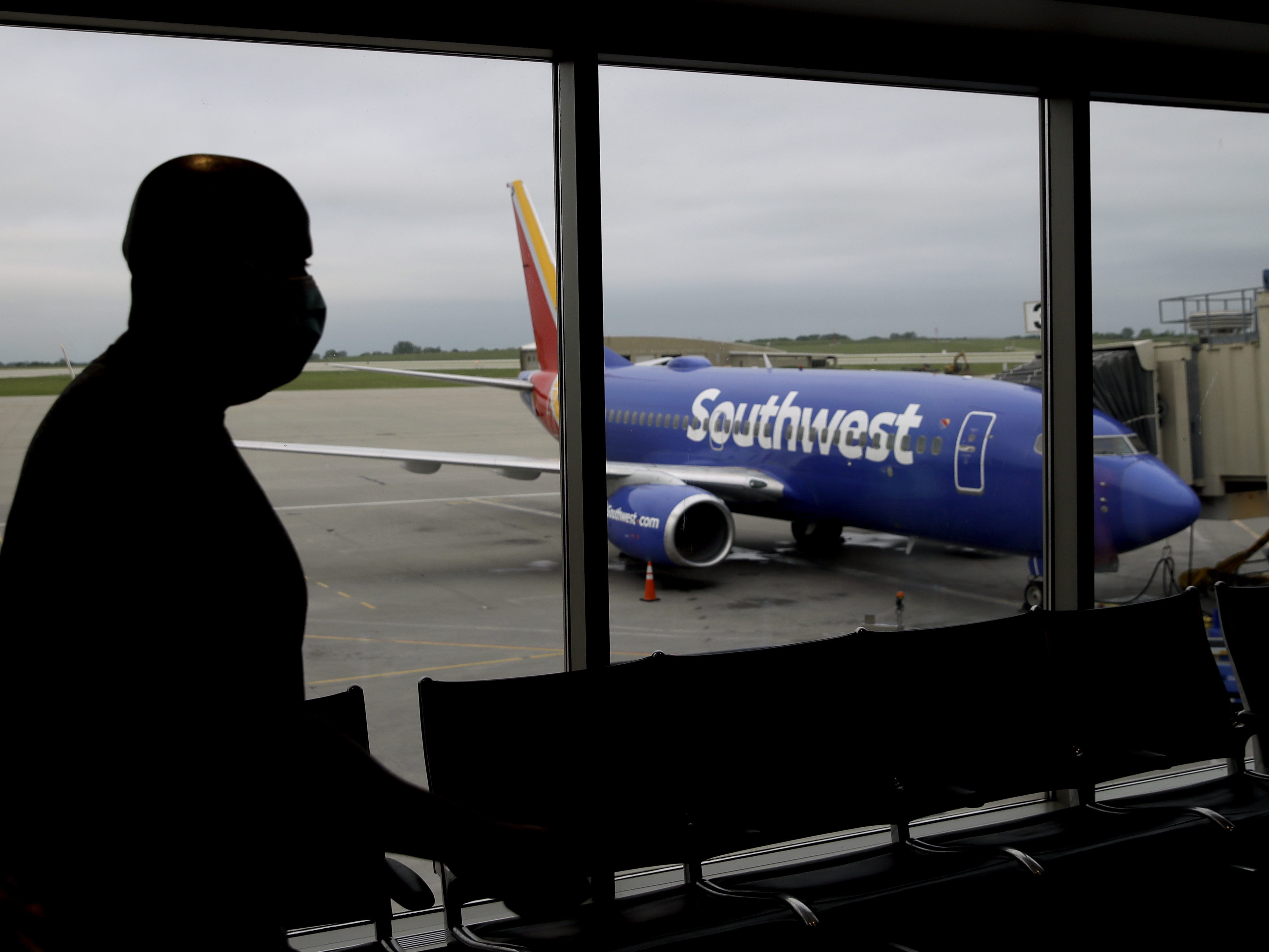 caption: A man wearing a mask prepares to board a Southwest Airlines flight at Kansas City International airport in Kansas City, Mo. Southwest and American Airlines are tightening their mask requirements at the end of July by doing away with exemptions for travelers over the age of 2.