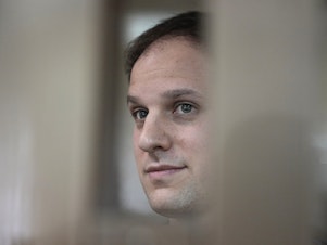 caption: <em>Wall Street Journal</em> reporter Evan Gershkovich stands in a glass cage in a courtroom at the Moscow City Court in Moscow, on Oct. 10. A court in Moscow on Tuesday extended his detention until Jan. 30, Russian news agencies reported.