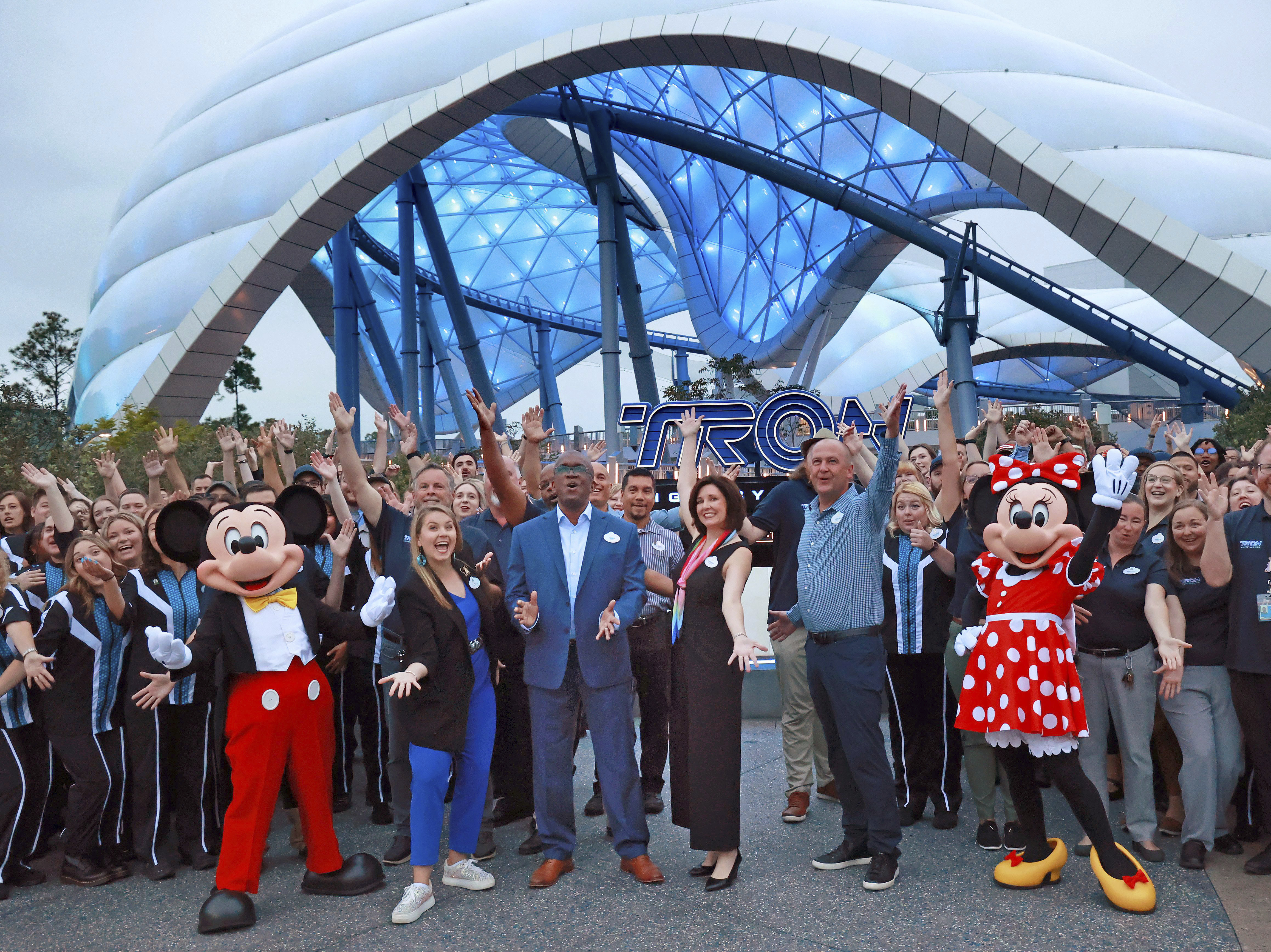 caption: Mickey, Minnie and cast members join Walt Disney World executives in a ceremony marking the official opening of Tron Lightcycle / Run at the Magic Kingdom in early April.