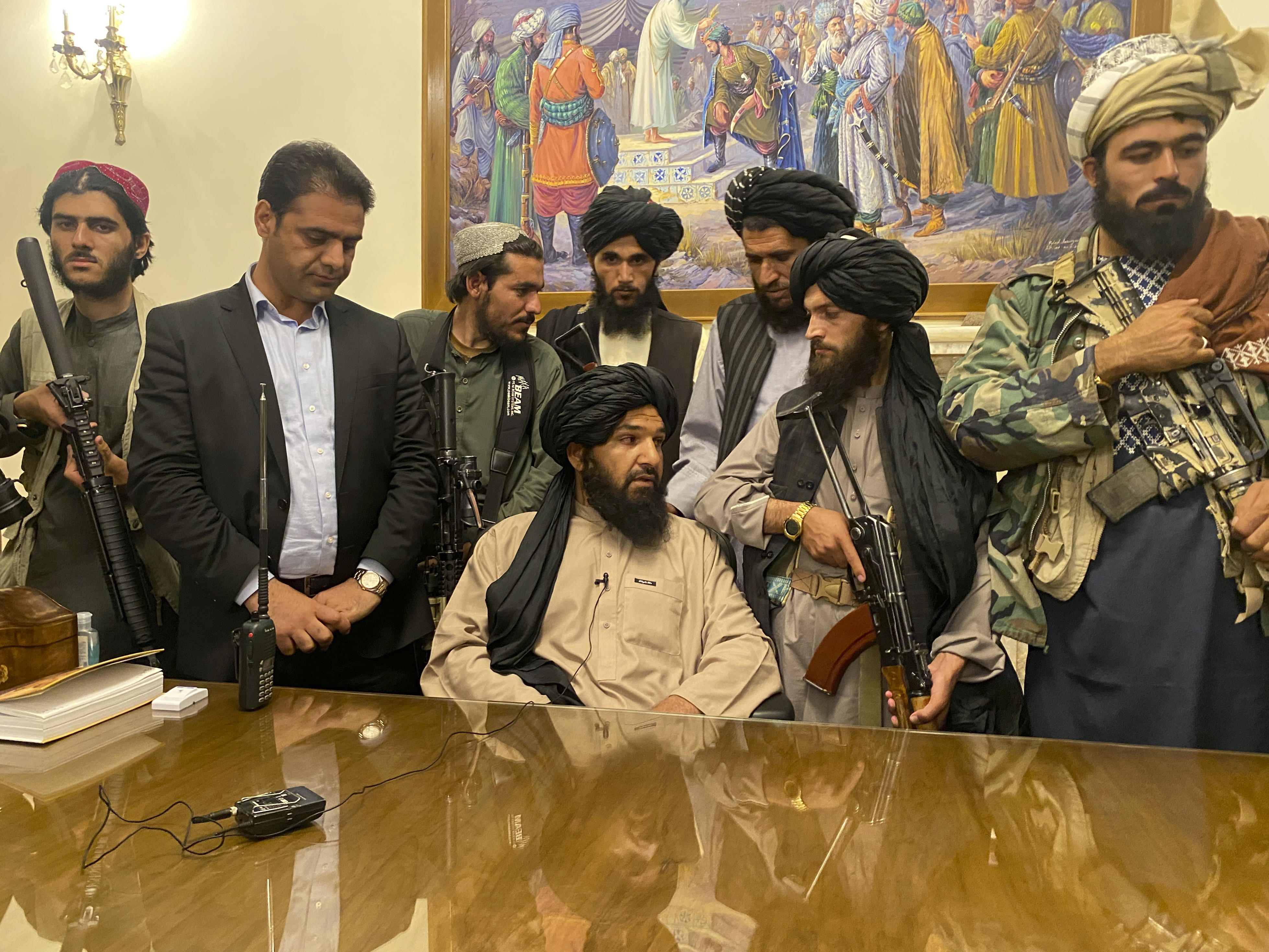 caption: Taliban fighters take control of Afghan presidential palace in Kabul on Sunday, after President Ashraf Ghani fled the country. The person second from left is a former bodyguard for Ghani.
