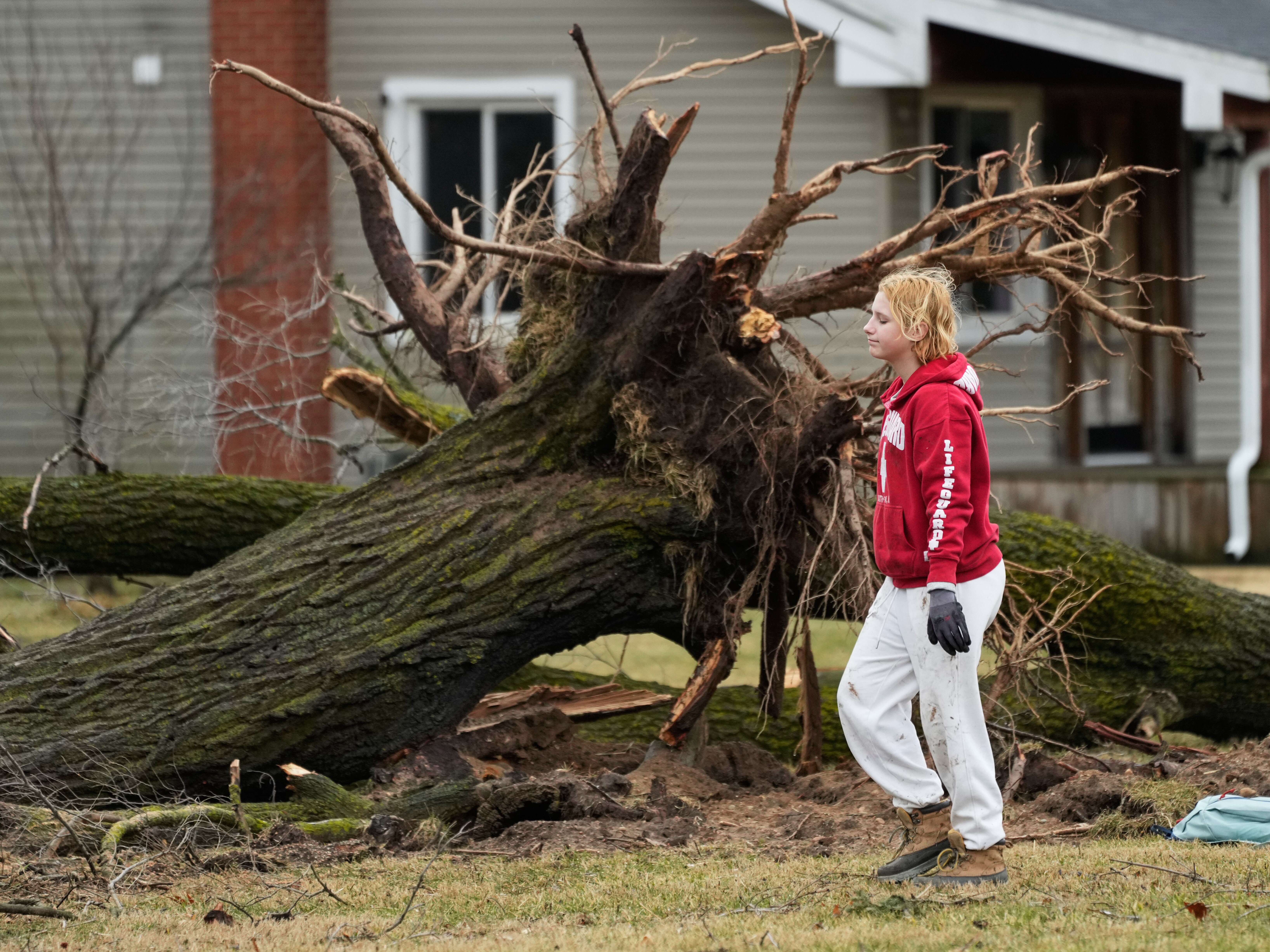 caption: A volunteer works to clear debris a day after a storm whipped up a tornado through the area, in Union City Mich. on Saturday.