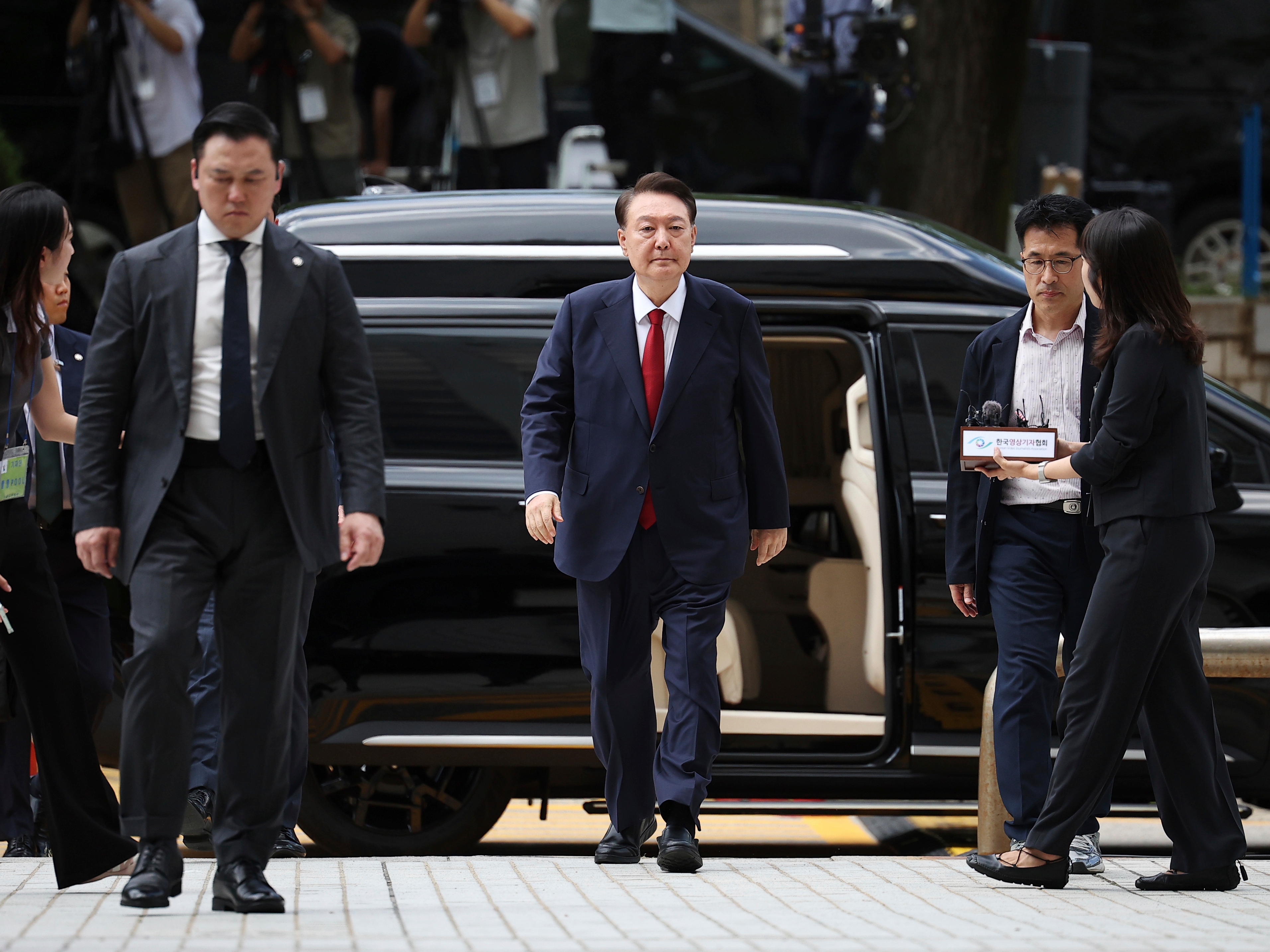 caption: FILE - Former South Korean President Yoon Suk Yeol, center arrives at a court to attend a hearing to review his arrest warrant requested by special prosecutors in Seoul, South Korea, July 9, 2025.
