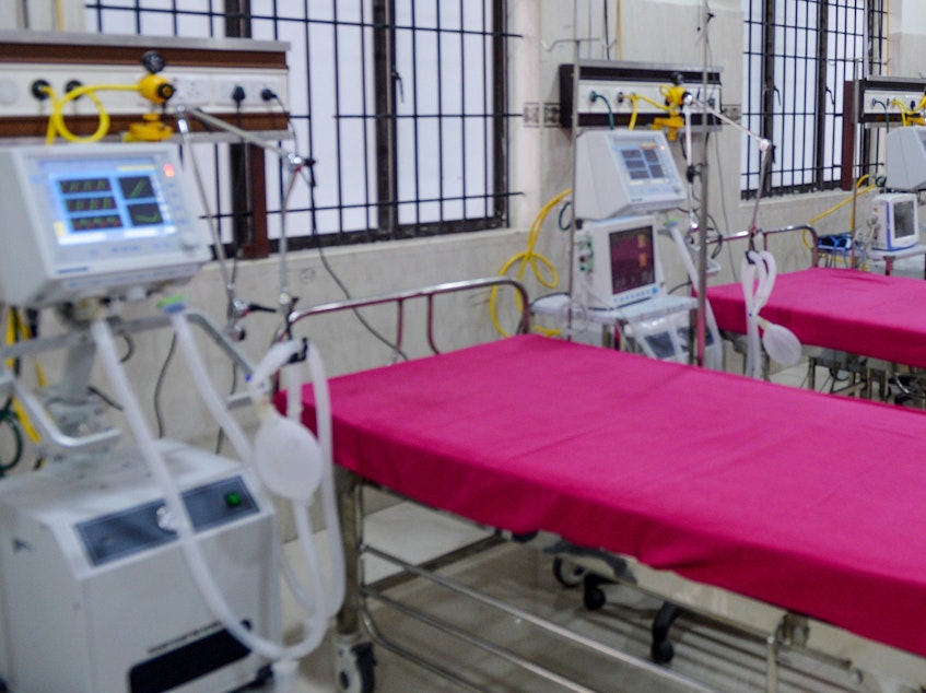 caption: A staffer checks on a ventilator in an intensive care unit in Chennai, India, Friday. States in the U.S. are coming up with plans for what to do if they run out of ventilators and other supplies.