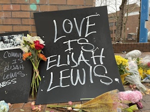 caption: A sign reads, "Love is Elijah Lewis" at a memorial on Monday, April 3, 2023. 
