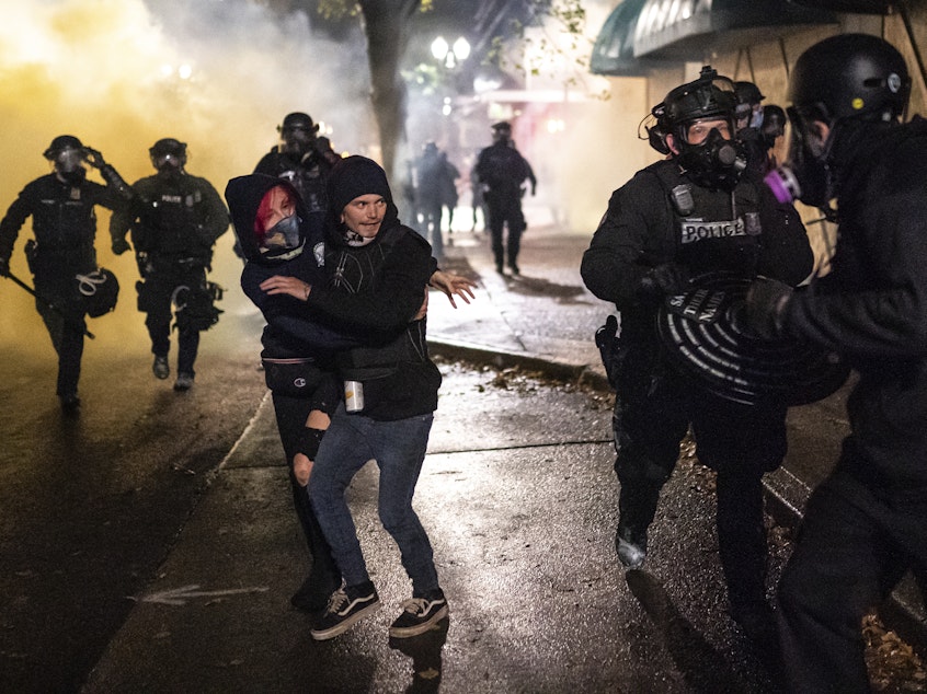 caption: Protesters look for an escape while Portland police disperse a crowd in Portland, Ore. Wednesday. Violent protests erupted following the results of a grand jury investigation into the police shooting death of Breonna Taylor.