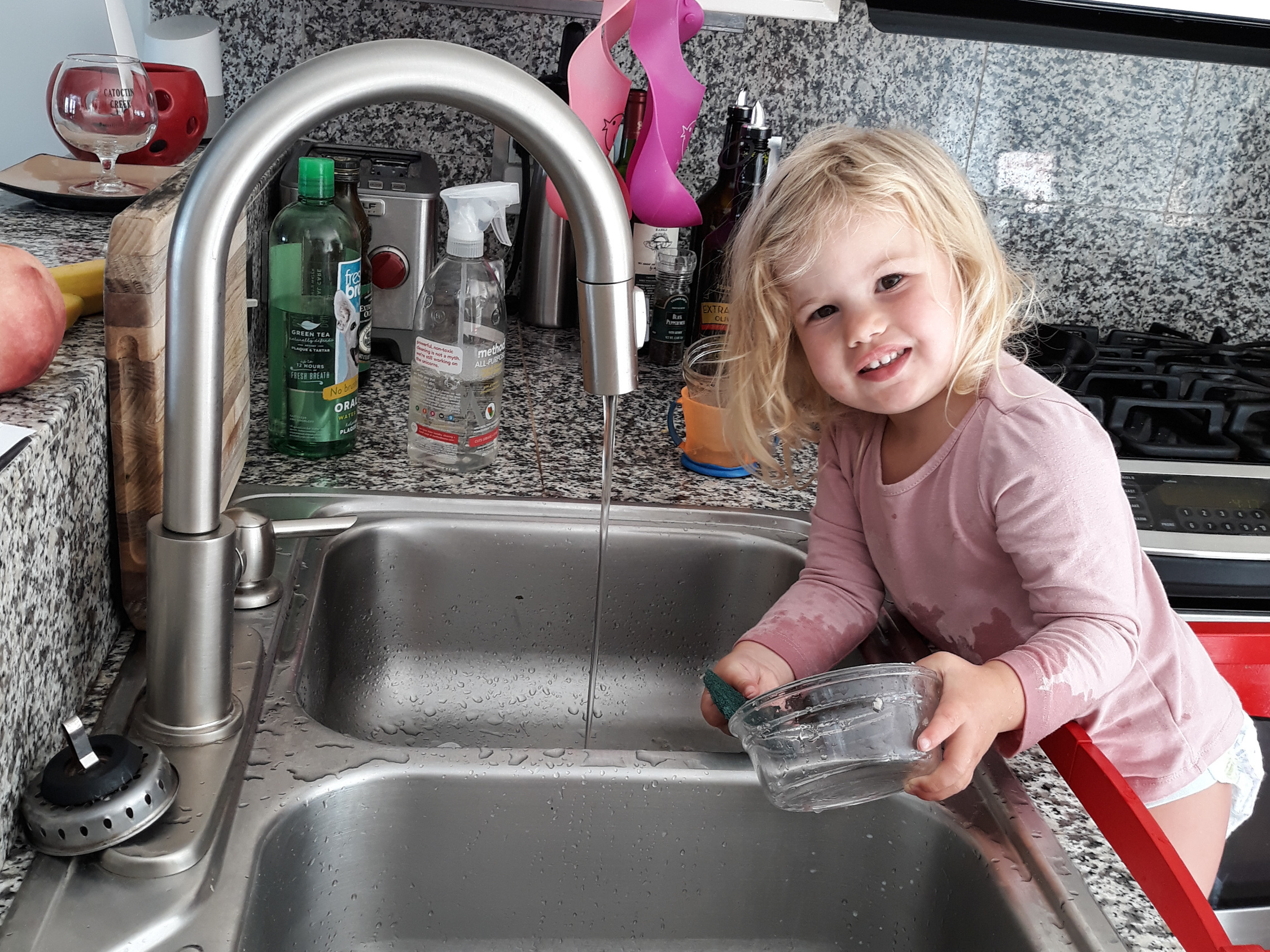 caption: Our correspondent Michaeleen Doucleff's daughter, Rosy, at age 2, as she does dishes voluntarily. Getting her involved in chores did lead to the kitchen being flooded and dishes being broken, Doucleff reports. But Rosy is still eager to help.
