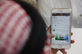 caption: A man reads Aramco's twitter page at a coffee shop in Jiddah, Saudi Arabia, Sunday, Nov. 3, 2019. 