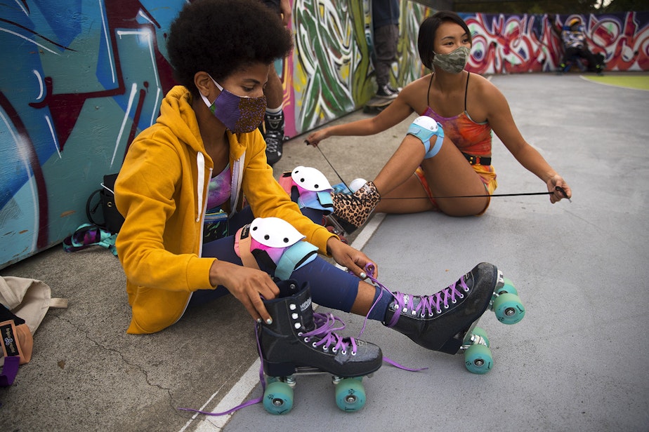 caption: Dalila Gittens, left, and Celina Macadangdang, medical residents at a Seattle-area hospital, untie their roller-skates after skating on Tuesday, September 22, 2020, at the Judkins Park sports courts in Seattle. 