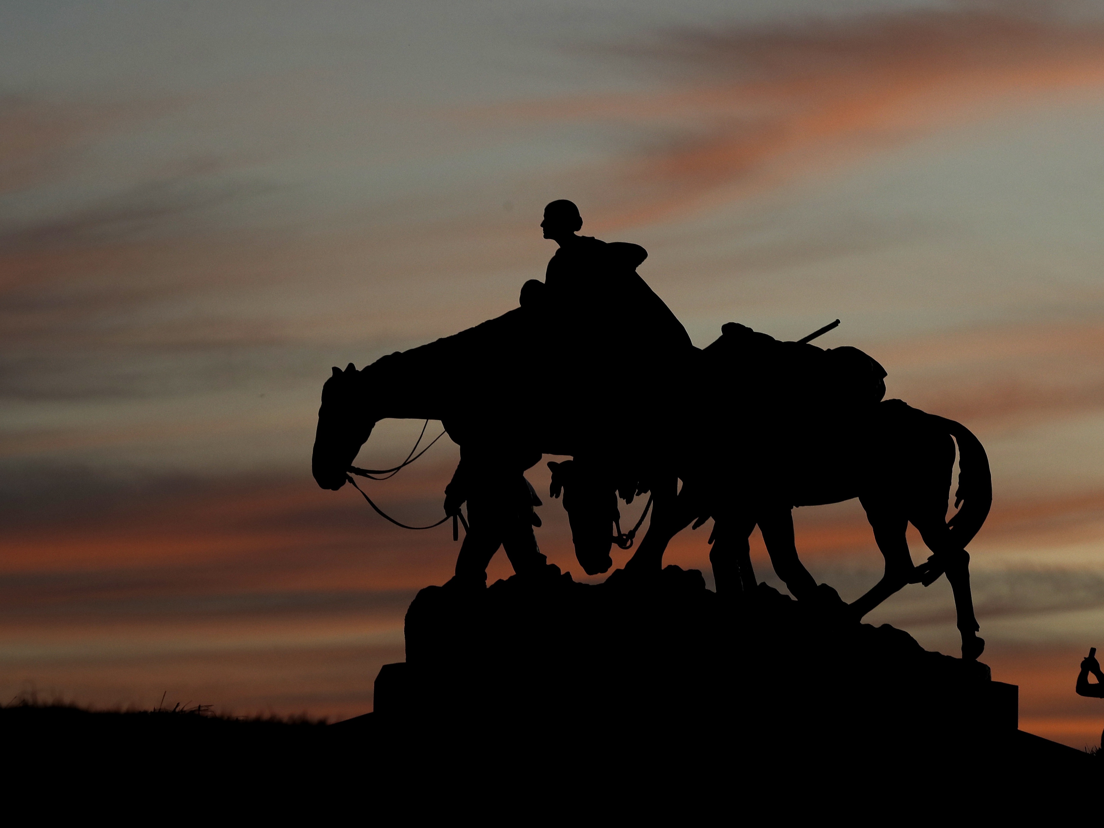 caption: A man takes a photo as he visits the Pioneer Mother Memorial as the sun sets Thursday, March 19, 2020, in Kansas City, Mo.