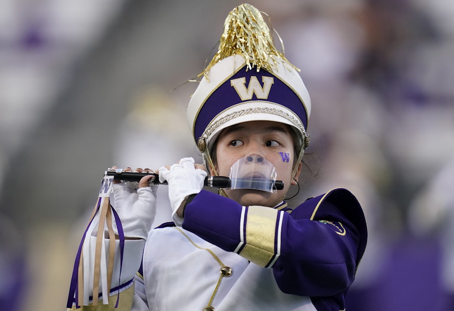 caption: A piccolo player with the Washington Marching Band performs with a mouth shield due to the COVID-19 pandemic before an NCAA college football game against California, Saturday, Sept. 25, 2021, in Seattle.