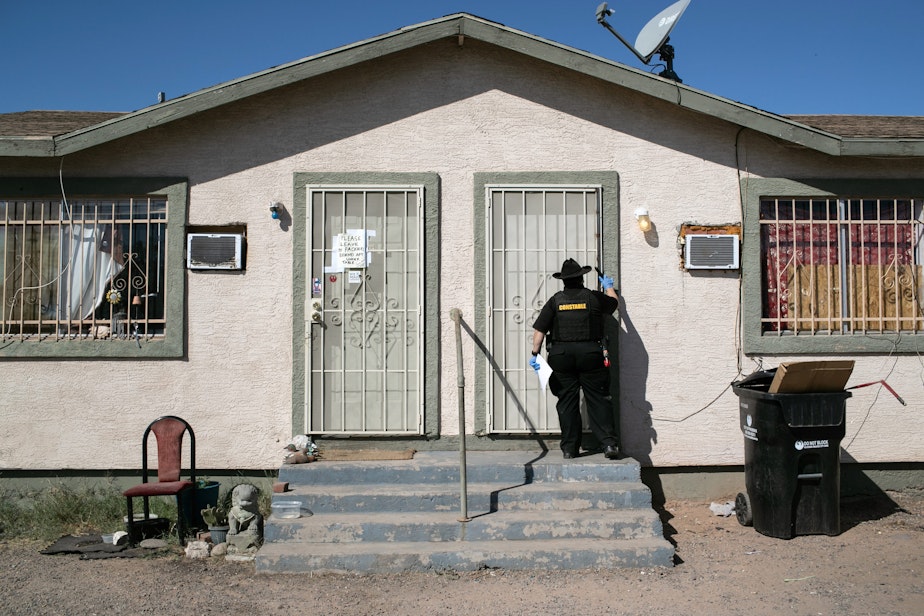 caption: A Maricopa County constable knocks on a door before posting an eviction order on Oct. 1, 2020 in Phoenix, Arizona. (John Moore/Getty Images)