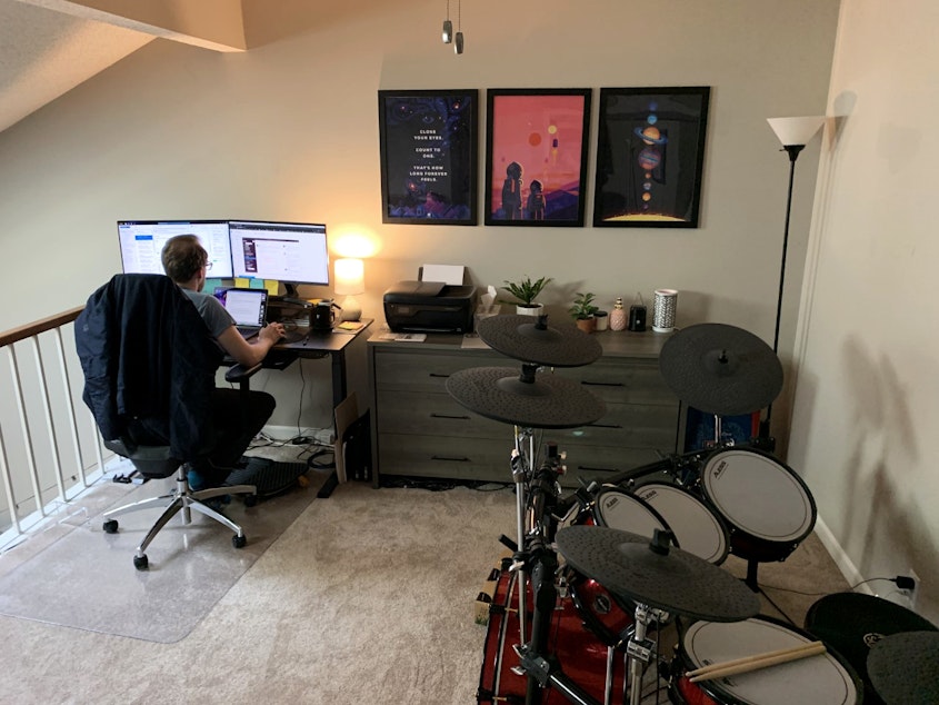 caption: Kevin Dole works from home next to his wife's bureau and near his drum set in the couple's small two-bedroom condo in Nashville, Tennessee.